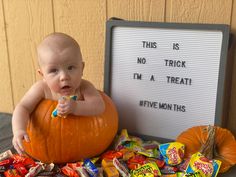 a baby sitting on top of a pumpkin with candy in front of it and a sign that says, this is not trick i'm a treat