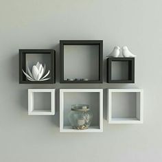 some white and black shelves with vases and other items on them in front of a gray wall