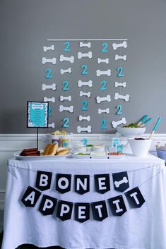 a dog themed birthday party with bone appetizers and food on a table in front of a gray wall