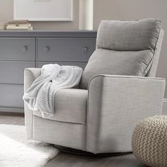 a chair with a blanket on it in front of a dresser and mirror, next to a white rug