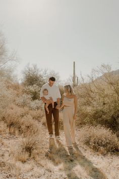 a man and woman are walking in the desert with their son, who is wearing a white shirt