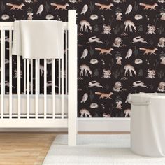 a baby crib in front of a wall with deer and pine trees on it