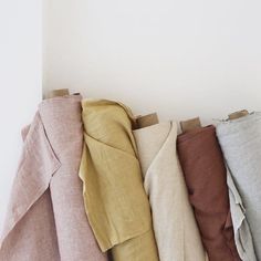 a row of different colored linens hanging on a white wall in a line up against the wall