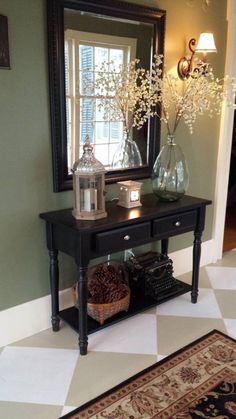 a black table with two vases on it and a mirror in the corner behind it