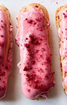 three doughnuts with pink icing and sprinkles on them