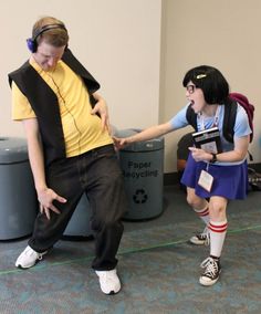 two people are dancing in the middle of an office area, one is wearing headphones and the other is listening to music