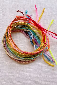 a bunch of different colored bracelets sitting on top of a white cloth covered table