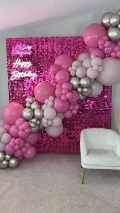 a room filled with balloons and a white chair in front of a pink sequin wall