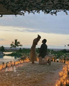 a man and woman standing next to each other in front of candles on the ground