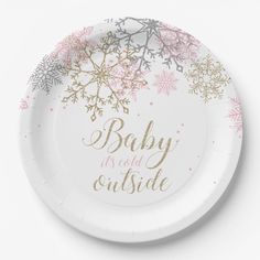 a white paper plate with pink and gold snowflakes on it that says baby is the outside