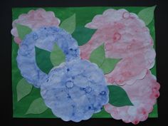 two paper flowers with leaves and water drops on them, one is pink and the other is blue