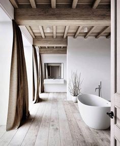 a bathroom with a tub and wooden floors in black and white photo by the door