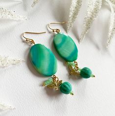 Teal Bird is a pair of handmade, ton-sur-ton earrings. Don't you immediately become happy when you see these earrings because of this summery color?! The pendant made of various materials hangs from the gold-coloured metal ear hook. The top one, the flat oval one, is made of teal (blue green) dyed mother-of-pearl (shell). Below are three charms: a goldcolored bird, a glass bead in a lovely teal color and a small charm made of three Toho glass beads in an aqua tone. Mother of pearl is a natural p Jade Beaded Drop Earrings, Jade Beaded Earrings As Gift, Beaded Jade Earrings As A Gift, Jade Beaded Earrings With Ear Wire For Gifts, Jade Beaded Earrings With Ear Wire As Gift, Green Beaded Jade Earrings, Jade Earrings With Dangling Beads As A Gift, Turquoise Jade Earrings For Gift, Green Jade Beaded Earrings For Gift