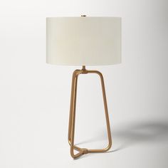 a table lamp with a white shade on the top and gold metal frame around it