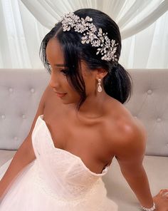 a woman in a wedding dress sitting on a couch wearing a bridal headpiece