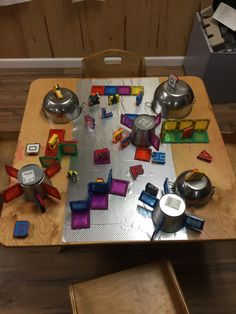 a wooden table topped with lots of different colored blocks next to pots and pans