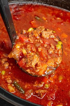 a ladle full of soup with meat and vegetables