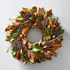 a wreath is hanging on the wall with leaves and other things around it to decorate