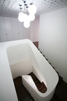 a room with white walls and wooden flooring, lights hanging from the ceiling above it