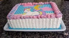 a birthday cake decorated with pink and blue icing on a marble countertop in the shape of a unicorn