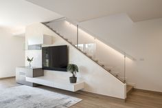 an empty living room with stairs and a tv on the wall in front of it