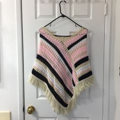 a pink and black crocheted ponchle hanging on a door