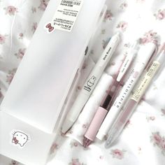 three pens are sitting next to each other in a white box on a floral sheet