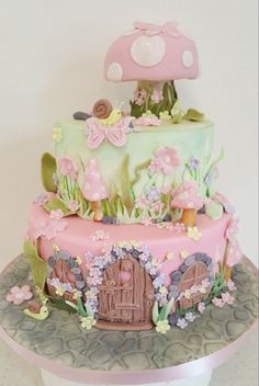 a pink and green cake decorated with flowers, mushrooms, and a mushroom topper