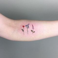 a woman's arm with three small flowers on the left side of her arm