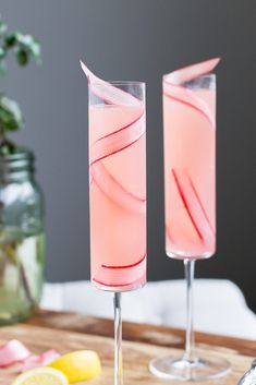 two glasses filled with pink liquid sitting on top of a wooden cutting board