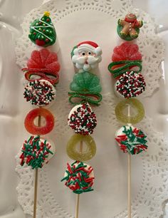 christmas cake pops decorated with candy and santa's helper on a white doily