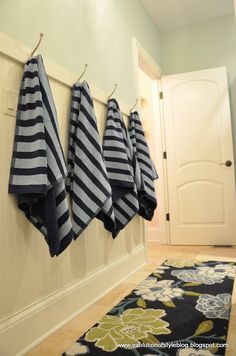 four blue and white towels hanging from hooks on the wall in front of a door