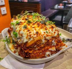 a white plate topped with lasagna covered in cheese and sauce on top of a table