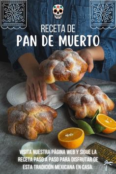 a person holding some bread on top of a table with oranges and other food