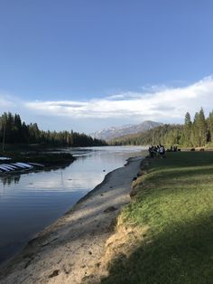 people are sitting at the edge of a lake