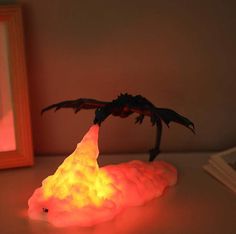 a glowing dragon figurine sitting on top of a table next to a framed photo