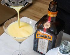 a drink being poured into a martini glass