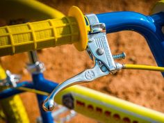 the handlebars and brake levers on a blue and yellow children's bike