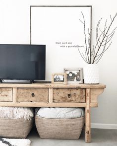 a tv sitting on top of a wooden table next to two baskets filled with pillows