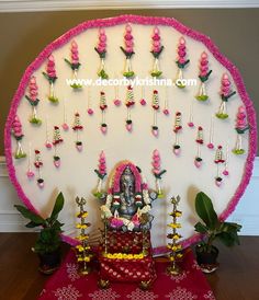 there is a ganeshi decoration on the wall with flowers and candles around it