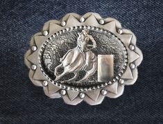 "\"The Barrel Racer\" womens western belt buckle is hand made in polished silvery pewter, 3 1/2 X 3 inches with a 1 1/2 inch belt loop. (standard belt size) Tooled with western patterns front & back this concho belt buckle sports a barrel horse & rider in high relief. Designed and handmade by the artist, USA." Vintage Silver Belts For Rodeo, Vintage Silver Belt Buckles For Western-themed Events, Silver Adjustable Belt For Rodeo, Adjustable Antique Silver Belt Buckles, Vintage Silver Belt Buckles For Rodeo, Vintage Silver Belt Buckle For Rodeo, Silver Western Belt Buckles, Western Silver Belt With Antique Buckle, Adjustable Silver Southwestern Belt Buckles