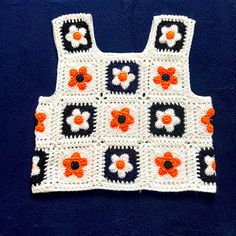 an orange and black crochet flowered top on a blue surface with white background