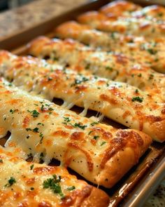 several slices of pizza with cheese and parsley on top, lined up in a baking pan