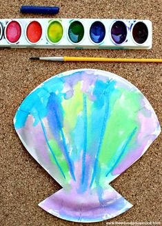 a paper plate with paint and watercolors on it next to a painting palette