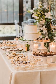 a table topped with lots of food and desserts next to a tall vase filled with flowers