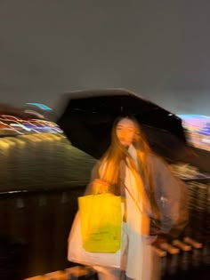 a woman walking down the street with an umbrella over her head and shopping bags in front of her