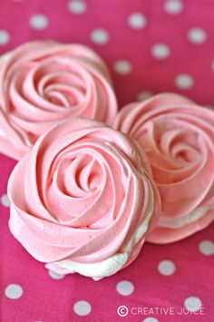 three cupcakes with pink frosting sitting on a polka dot tablecloth