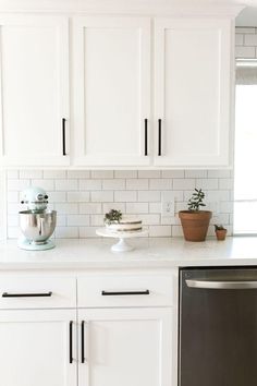 a kitchen with white cabinets and black trim on the countertops, including a dishwasher