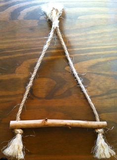 a piece of wood with rope hanging from it's sides on a wooden table