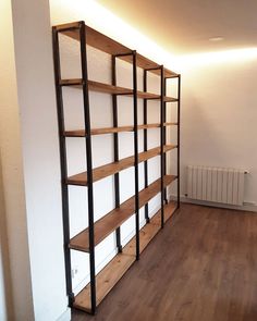 an empty room with wooden floors and shelving unit on the wall next to a radiator